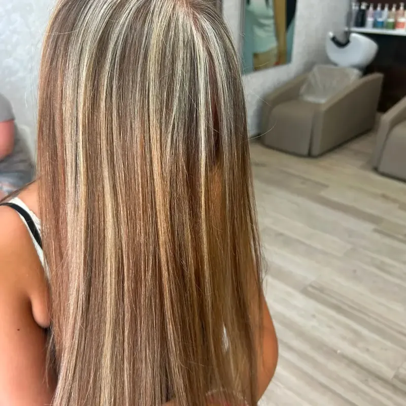 Melena lisa con mechas rubias; al fondo, los lavacabezas del salón