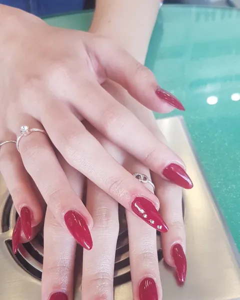Manicura en rojo con uñas almendradas y pequeños detalles de pedrería